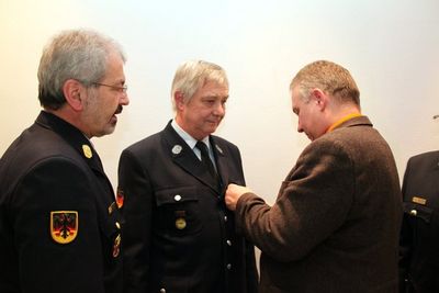 KBR Fredi Weiß überreicht Richard Reiser die Ehrenurkunde für 40 Jahre aktiven Feuerwehrdienst, Bürgermeister Markus Dollacker steckt ihm das Feuerwehrehrenzeichen an.