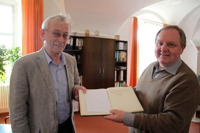 Der damalige Klosterdirektor Pater Josef Wenzl (li.) und der jetzige Direktor des Klosters der Salesianer in Ensdorf, Pater Christian Liebenstein, betrachten den unscheinbaren Eintrag im Gästebuch des Klosters.