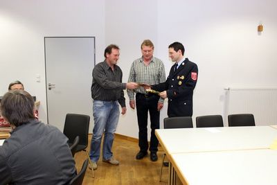 Kommandant Johann Westiner (li.)und Vorsitzender Joachim Hantke überreichten dem Ensdorfer Feuerwehrkommandanten Michael Ott (re.) in Goldpapier verpackte Geschenke.