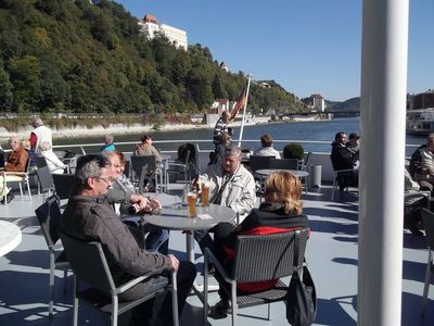 In Passau sitzen Teilnehmer auf dem Oberdeck der „Sissi“, im Hintergrund die Veste Oberhaus.