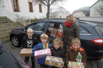 Kinder des Kindergartens St. Jakob helfen Pfarrgemeinderätin Maria Leikam beim Verladen der Weihnachtspäckchen POMOC.