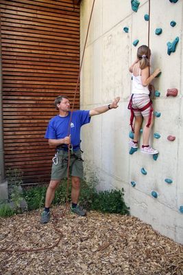 Robert Reiner sichert die achtjährige Eva an der Kletterwand im Klostergarten.