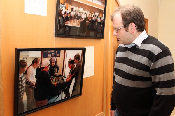 Robert Rojzman betrachtet ein Bild der interreligiösen Fotoausstellung, das jüdische Jugendliche beim Kickerspiel zeigt.