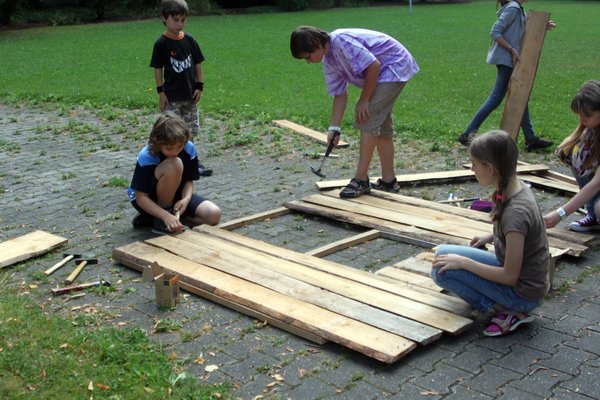 Eifrig werkeln die Kinder, damit die Holzhäuser rechtzeitig fertig werden.