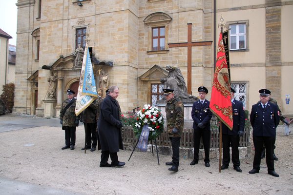 Bürgermeister Markus Dollacker (li.) und Erich Brem, Vorsitzender des Krieger- und Reservistenverein legen, umrahmt von der Ehrenabordnung der Reservisten und der Fahnenabordnungen von Krieger- und Reservistenverein und Freiwilligen Feuerwehr im Gedenken