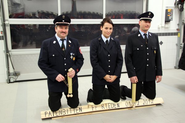 Hartes Knien auf Holzscheiten beim Patenbitten: V. li, :Riedens Feuerwehrvorsitzender Herbert Scharl, Festmutter Steffi Igl und Feuerwehrkommandant Jürgen Reinwald.