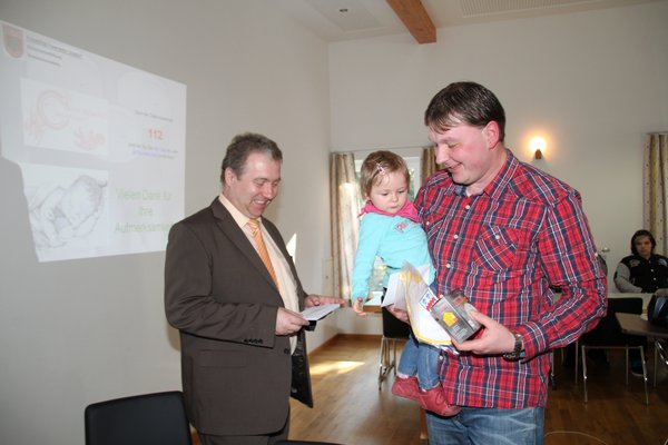 Bürgermeister Markus Dollacker bei der Übergabe der Geschenke an die neuen Gemeindebürger und deren Eltern.